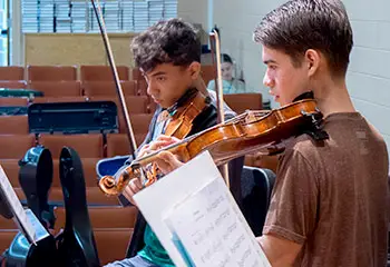 Two young men playing violins