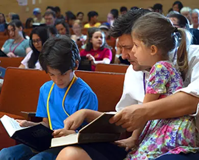 father teaching son to read hymnal