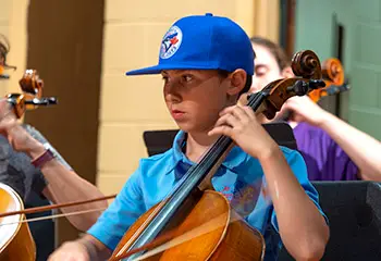 boy in blue hat playing cello