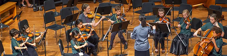 small children playing violins and cellos